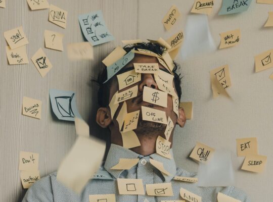 man sitting with stickynotes over face and body