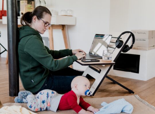 mother typing on laptop next to baby