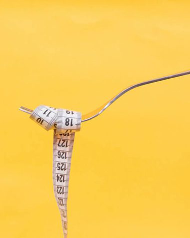 measuring tape wrapped around fork against a yellow background