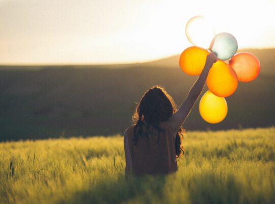 woman in field with balloons